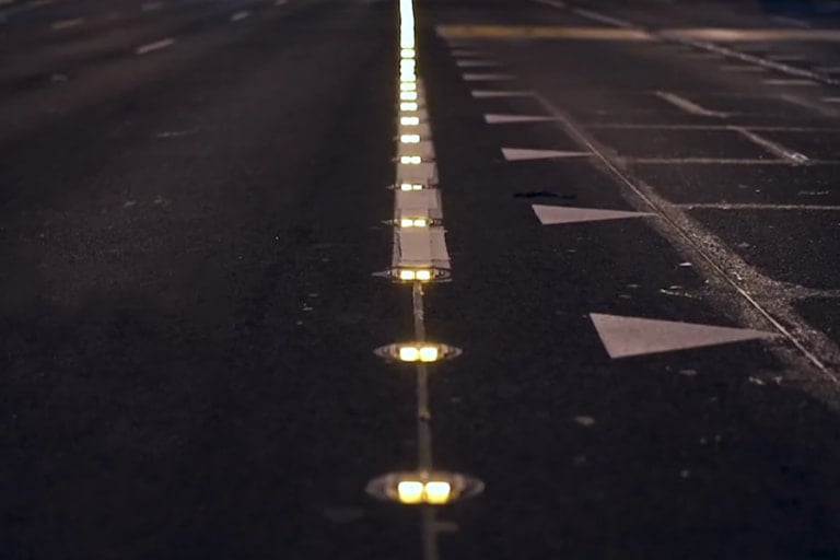 Mehrspurige Straße bei Nacht, eine Reihe leuchtender Road Studs markiert die Trennlinie